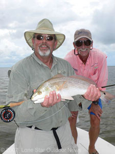 Steve Faris holds his first  Red Drum caught on a fly. Faris was using a white Scates Shrimp pattern. Capt. Chuck Scates of Rockport Texas looks on. Photo by David J. Sams